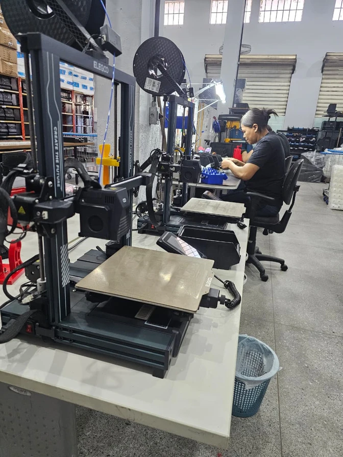 Profissional trabalhando na produção Allcanci ao lado de equipamentos de impressão 3D